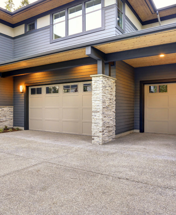 Elegant wooden carriage garage doors installed on a craftsman cottage home surrounded by nature in Ontario. These garage doors combine a rustic wood finish with modern insulation and quiet operation. Installed by Priority Garage Doors, they enhance both aesthetics and functionality for residential properties.